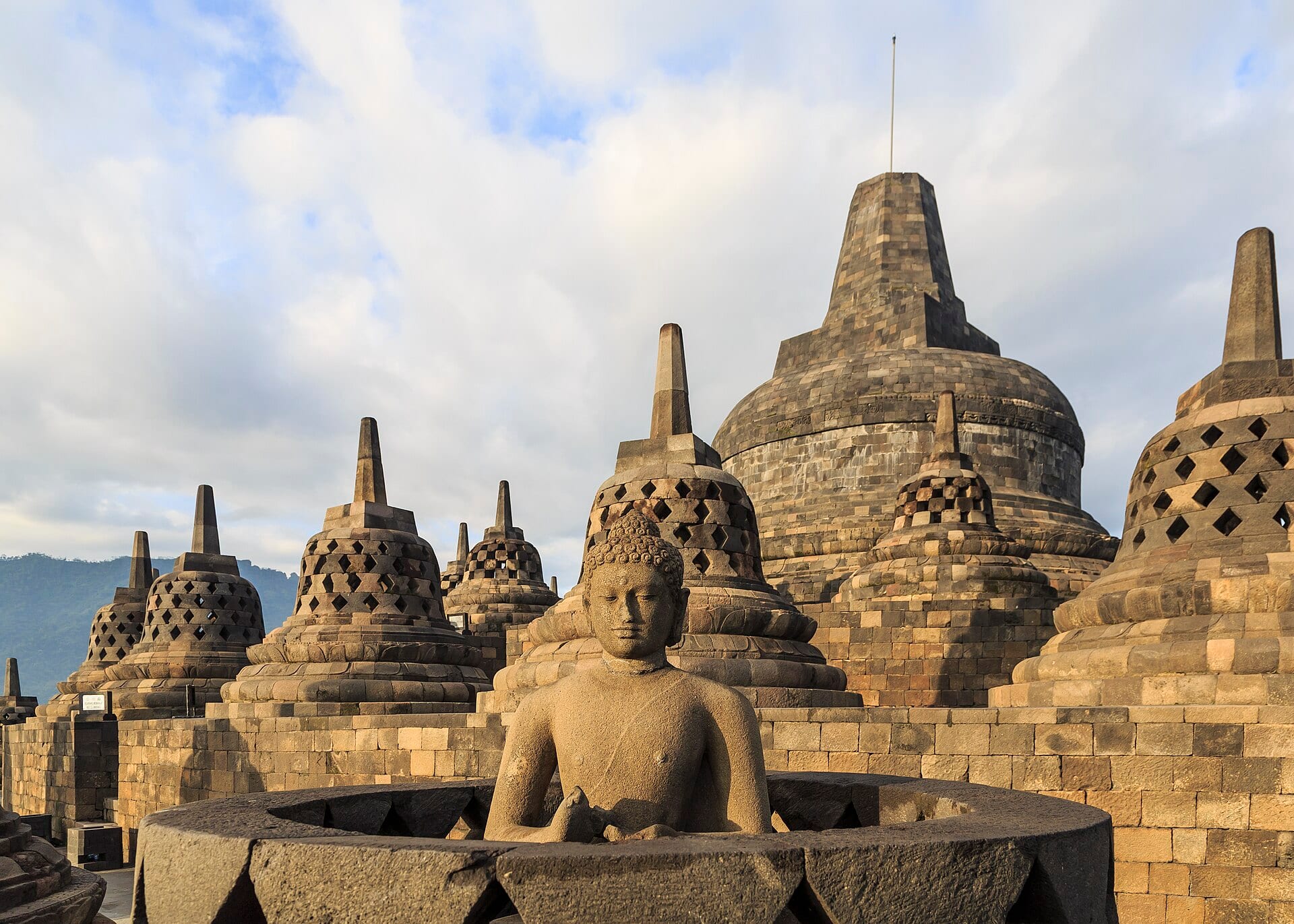 The bell-shaped stupas and a seated Buddha at Borobudur temple in Central Java, Indonesia