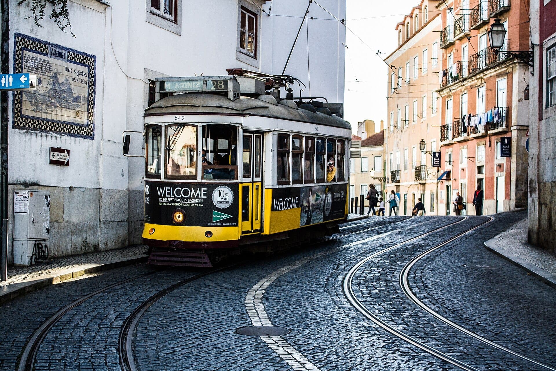 A yellow Tram 28 on a cobbled street in Lisbon